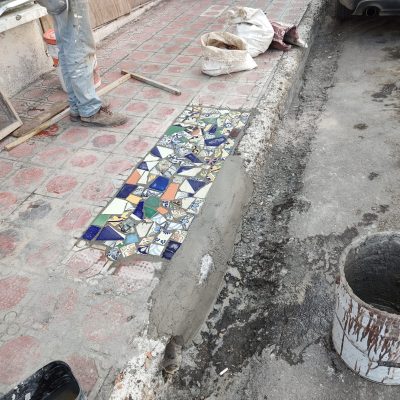 Reparan banquetas con pedacería de mosaico